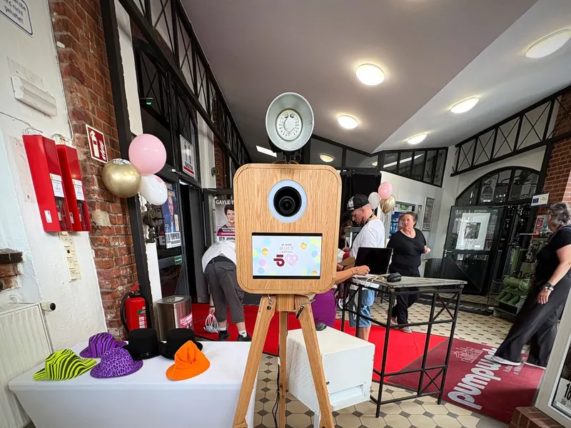 Fotobox aus Holz im Eingang einer Feier, daneben der Requisitentisch