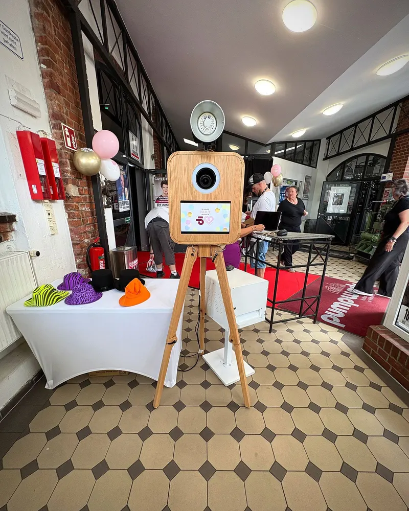 Fotobox aus Holz im Eingang einer Feier, daneben der Requisitentisch