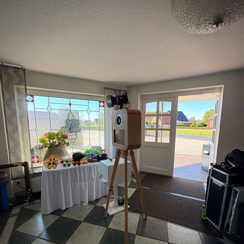 Klassische Holz-Fotobox auf weißem Tischrock vor Buntglas-Fenster