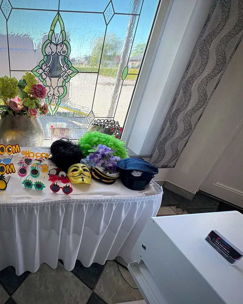Props-Tisch mit Brillen, Masken und Blumen vor Buntglasfenster